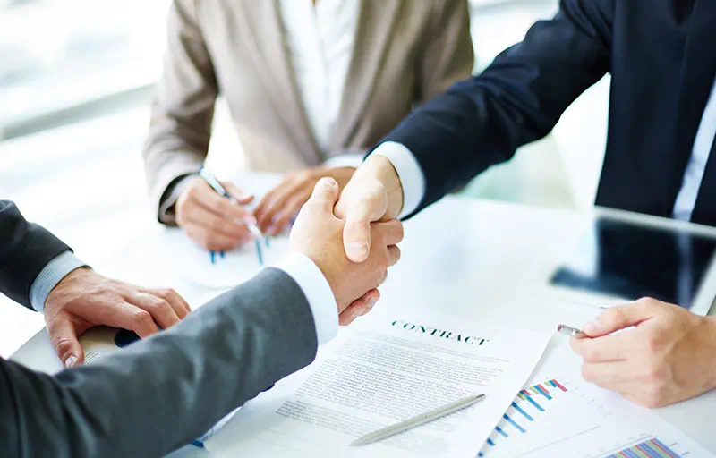 Two business men shaking hands over a contract.