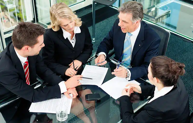 A group of business people discussing a contract in a meeting room.