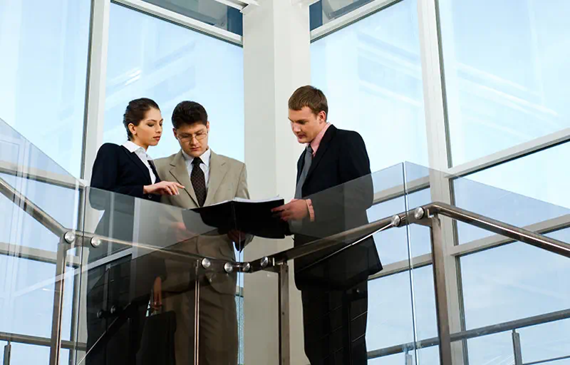 Leasing & Tenant Representation Three people looking over notes in a modern office building.