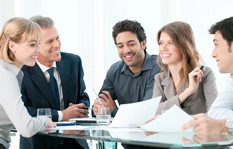 Property Sales & Acquisitions A group of business people discussing a contract in a meeting room.