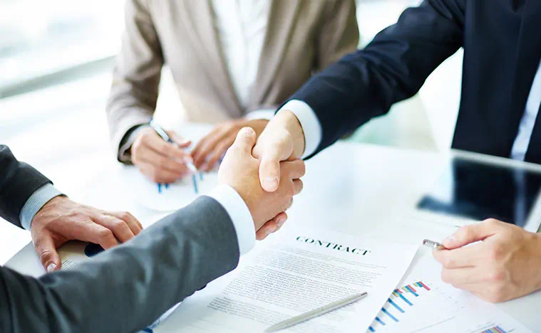 Client First Approach Two business man shake hands over a signed contract.